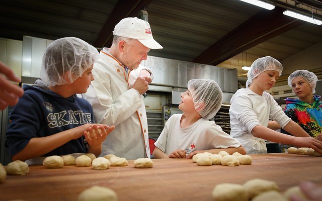 Naturbackstuben-Chef Reinhard Honeder und Jugendrotkreuz-Kinder aus Linz und Urfahr-Umgebung beim gemeinsamen Backen.