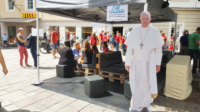 „Chillen auf eigene Gefahr“ in einem mit Sitzmöglichkeiten und Handyladegeräten ausgestatteten Pavillonzelt. Beliebt: ein Papst Franziskus Aufsteller als Selfie-Motiv.