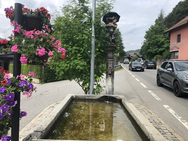 Idylle und Verkehrshölle im Reither Ortsteil Leithen: Von hier aus (Brunnen bei Bushaltestelle) bis zum Ortsende (Hintergrund, entlang der linken Straßenseite) soll ein Gehsteig errichtet werden.