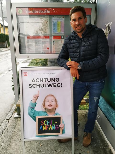 Sebastian Lankes mit "Achtung, Schulweg!"-Plakat bei der Bushaltestelle Siedlerstraße in Gnigl