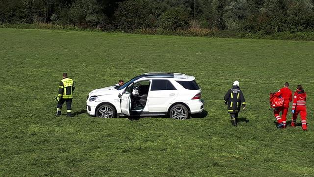 Einsatzkräfte kümmern sich hinter dem Unfallfahrzeug um den Schwerverletzten neben der A12 bei Wörgl.