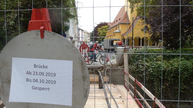 Zwei überraschte Radfahrer, die wegen einer plötzlich weggerissene Brücke, wieder zurück an den Start dürfen.
