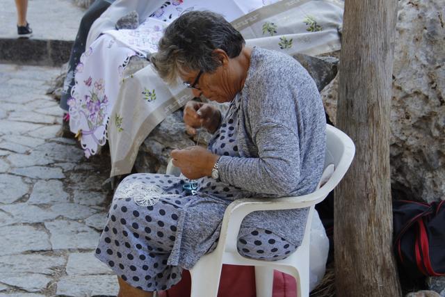 Deckchen und Tischdecken werden von griechischen Frauen, entlang des Weges zur Akropolis von Lindos, günstig angeboten.