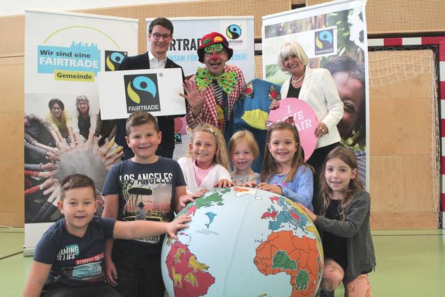 FairTrade Clown Hugo mit Florian Scheicher, Rosa Bock und den Kindern der Volkssschule Stadt, die „unsere Welt“ in Händen halten.