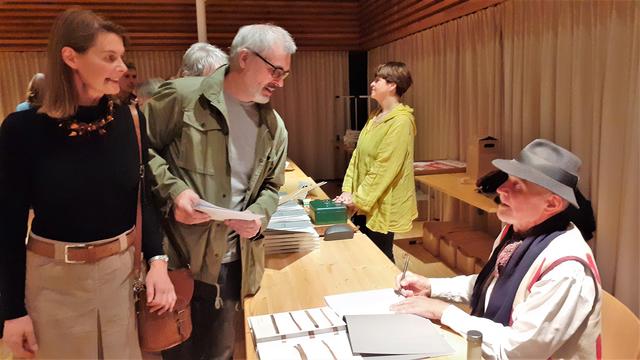 Wolfgang Männer, der reisende Künstler mit Hut, signiert sein neues Werk.  | Foto: RAXmedia