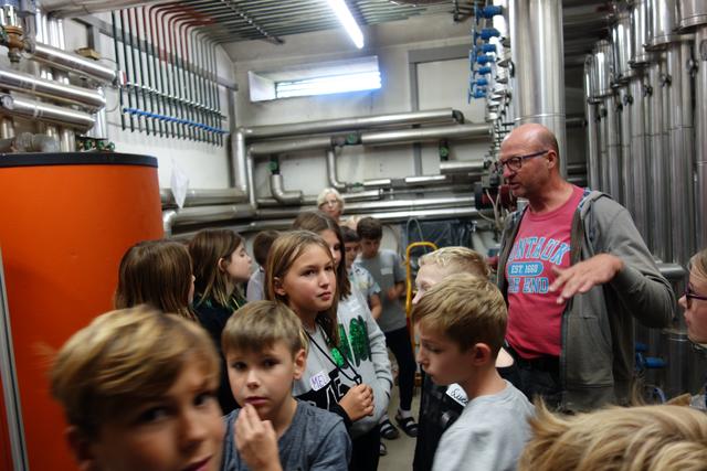Das Energieteam der NMS Leibnitz II und Schülern im Heizungsraum der Schule mit dem Schulwart, der die Heizung erklärt.