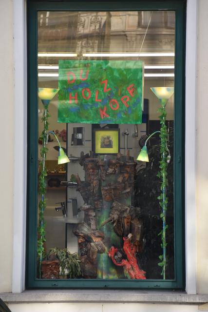 Holzköpfe als Kunstwerk im Fenster des Installateurs.