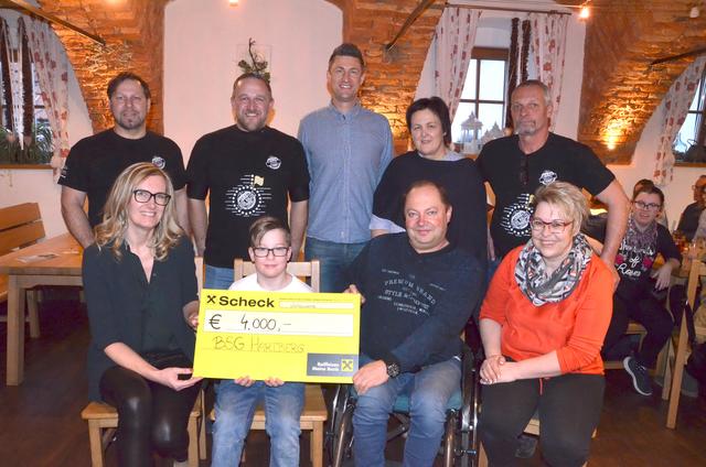 Andrea Konrad von der Raiffeisenbank (li) überreichte im Beisein des Seidl Rallye Teams (hinten) und von BSG Vertretern die Spende an den kleinen Jakob.
