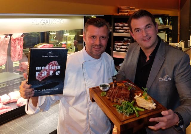 „Medium Rare – Steak: Die Hohe Schule“ wurde bei den Gourmand Cookbook Awards 2020 als Österreich-Champion ausgezeichnet, hier zu sehen el Gaucho-Küchendirektor Christof Widakovich mit seinem Schwager Michael Grossauer, die das Sieger-Kochbuch mit dem dazugehörigen Corona-Steak präsentieren.