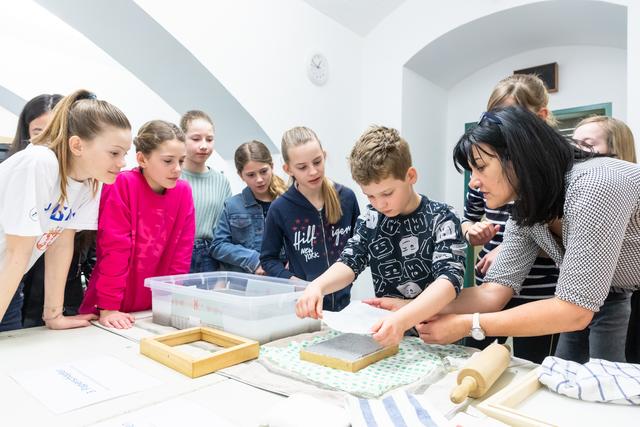 Gespannt: Unter der Anleitung von Marianne Kiem lernen die Kinder, wie Papier von Hand geschöpft und weiterverarbeitet wird.