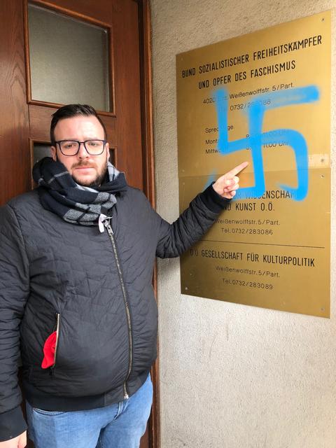 Der Vorsitzende des Bundes Sozialdemokratischer FreiheitskämpferInnen Samuel Puttinger vor dem beschmierten Schild.