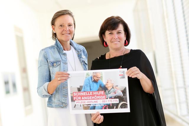 Caritas-Geschäftsführerin Andrea Anderlik und Sozial-Landesrätin Birgit Gerstorfer präsentieren ein Plakat zur Pflege-Hotline.