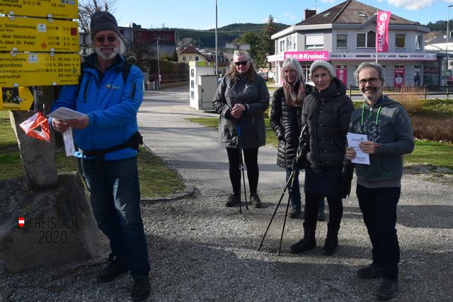 Alpenvereinsobmann Gerd Simon zwickt seine Startkarte beim Wanderstein Freistadt, daneben die Wanderer der Eröffnungstour mit dem Organisator Martin Reindl