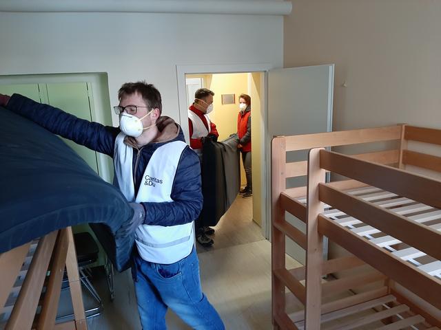 Helfer der Caritas beim Betten herrichten der neuen 24-Stunden-Unterbringung in der Plainstraße 83.