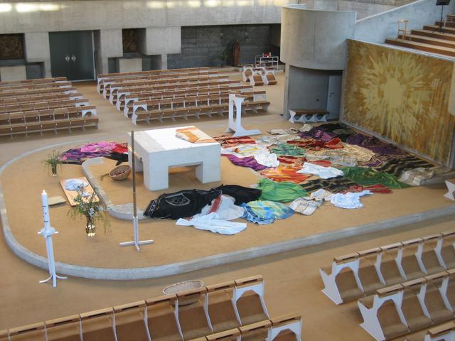 Rund um den Altar sind leere Meßgewänder drapiert.