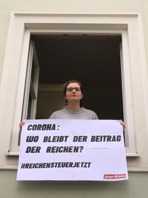 Die Jungen Linken hängen zum Tag der Arbeit Plakate von Balkonen und Fenstern.