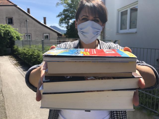 Die entliehenen Bücher aus der Stadtbibliothek werden mit Mundschutz zurückgegeben.
