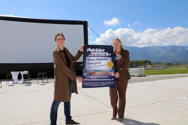 Initiatorin und Dirigentin Elisabeth Fuchs mit Flughafengeschäftsführerin Bettina Ganghofer vor der Leinwand des Salzburger Autokinos beim Flughafen.