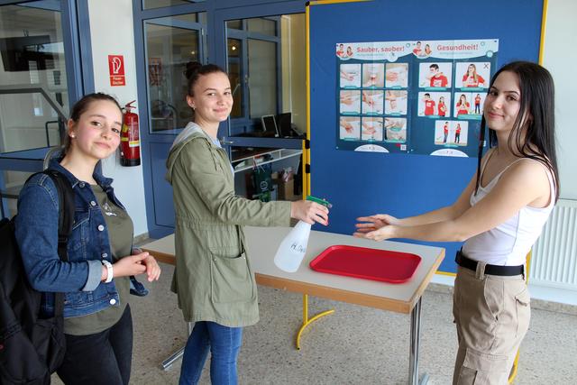 Maya, Kosovara und Flavia bei der Händedesinfektion am Eingang