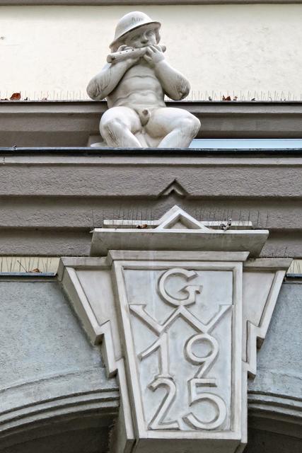 Am Eingang beim Nietzsche-Platz wird man von mehreren Figuren über dem Portal empfangen. Der Musikus ist eine davon.