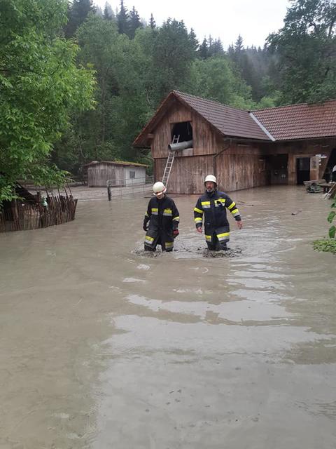Feuerwehrmänner kämpfen sich durch das Wasser.