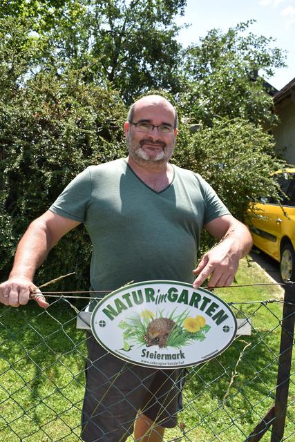 Markus Triendl zeigt die "Natur im Garten"-Plakette, die für den Privat-Garten in Pichling ausgegeben worden ist.