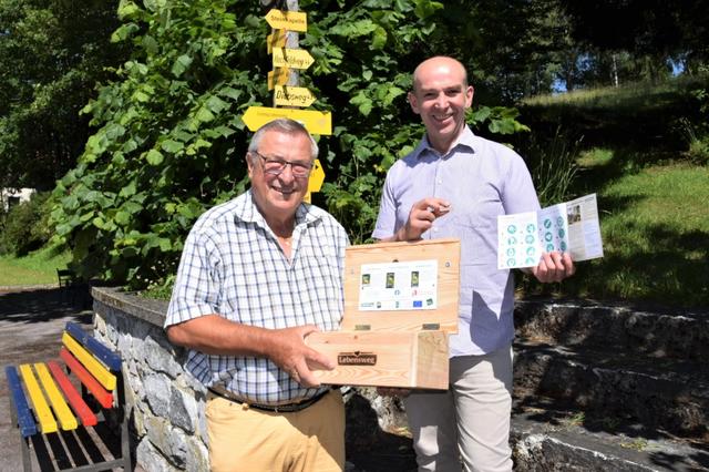 Lebensweg-Vereinsobmann Konrad Friedl und Lebensweg-Initiator Dieter Juster präsentieren die Stempelbox und den Wanderpass.