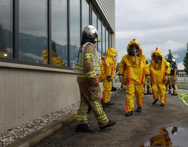 Feuerwehrmänner rücken mit Schutzanzügen und Atemschutzmasken aus.