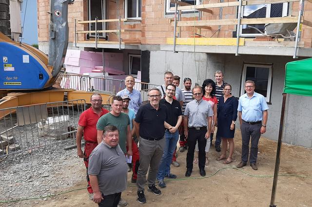 Vertreter der Wohnungsgenossenschaft Lebensräume, der Gemeinde und der Baufirmen stießen auf die Fertigstellung des Rohbaus an.