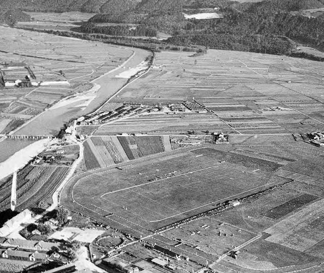 Luftbild aus dem Jahr 1946, auf dem der große Lagerkomplex des ns-Verfolgungsapparats in Innsbruck-Reichenau in der linken oberen Bildhälfte deutlich zu erkennen ist : an der hölzernen Innbrücke das Gasthaus Sandwirt, am Inn gelegen ein ehemaliges Kriegsgefangenenlager, rechts davon das Areal des ehemaligen Arbeitserziehungs- und Gestapo-Lagers.