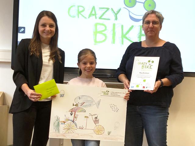 (von links) Schulleiterin Katharina Leitner und Klassenlehrerin Brigitte Schatz freuen sich mit der Preisträgerin Flora Kirchmair aus Seefeld über den zweiten Platz im Bezirk beim Crazy Bike Malwettbewerb von Klimabündnis Tirol.