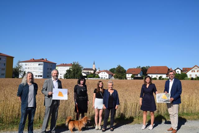 Stadtrat Herbert Höpfl, Vizebürgermeister Martin Litschauer, Heli Dunglers Ehefrau Iona Dungler, Tochter Nina Närr, Mutter Irmtraut Dungler, Stadträtin Marlene Lauter und Stadtrat Thomas Lebersorger und Hund Cupper vor dem Grundstück der zukünftigen "Heli-Dungler-Siedlung".