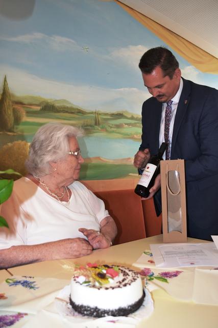 Bezirksvorsteher Marcus Franz überreicht Gertrude Switil eine Flasche Rotwein als Geschenk.