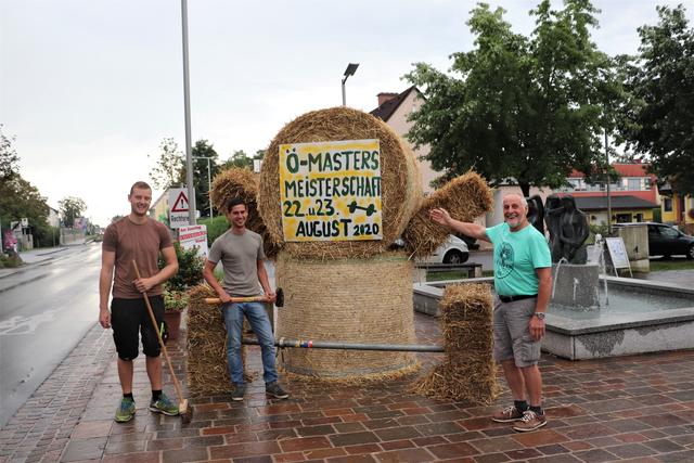 LJ-Obmann Daniel Füller, JVP-Obmann Christoph Pellischek und Hans Gruber (re) machen mit dem Gewichtheber aus Stroh auf die Masters-Meisterschaft aufmerksam.  | Foto: Edith Ertl