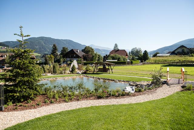 Der herzförmige Teich bildet den Mittelpunkt des Außenbereichs, dahinter der Kraftplatz mit Naschgarten.