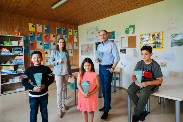 Schultüten für den Schulstart: Oliver Heinrich, Finanzvorstand von Infineon Austria, und Mag. Marion Fercher, kaufmännische Geschäftsführerin der Caritas Kärnten, mit Kindern des Caritas Lerncafés in Villach.