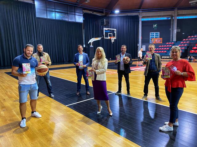 Mario Riemel (l) präsentierte die Broschüre "Sport in Favoriten" stilecht in einer Baskteball-"Arena". Mit dabei auch Bezirksvorsteher Marcus Franz (3.vl).