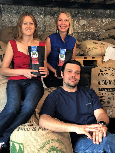 Sitzend auf den Säcken in denen die Bohnen für die neue "Tiroler Röstung" stecken: Antonia Kriechbaum vom Weltladen Innsbruck/Julian Schöpf von Brennpunkt OG/Iris Teyml von der ARGE Weltläden