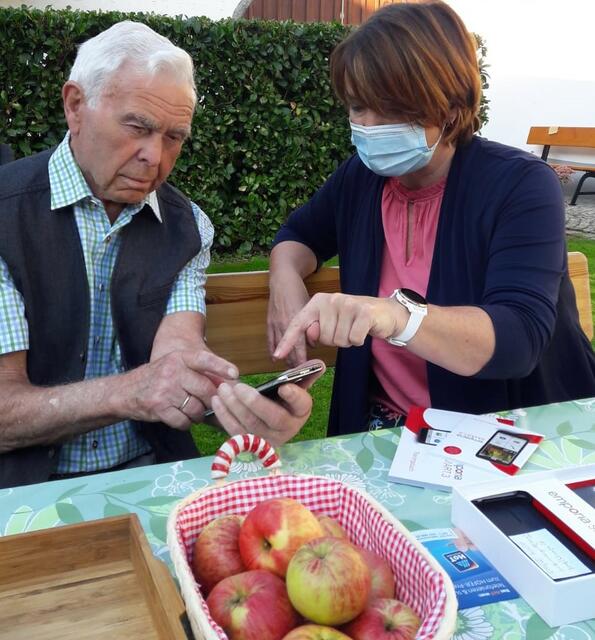 Emporia Schulungsleiterin Sigrid Prammer erklärt Josef Wiesinger, wie er mit WhatsApp Fotos bekommen und anschauen kann.