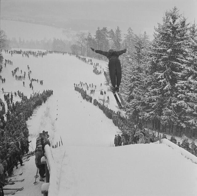 Damals 1941: Skispringen am Pöstlingberg
Der Pöstlingberg als Hausberg der Linzer Bevölkerung wurde mit Aufkommen des Skisports um 1900 auch im Winter ein beliebtes Ausflugsziel. Rodeln, Skilaufen und auch Skispringen wurden besonders auf der „Mayrwiese“ betrieben. Ein erstes Wintersportfest fand 1907 statt; es gab damals auch schon eine Sprungschanze. Sportliche Wettkämpfe zogen bis weit nach dem Zweiten Weltkrieg stets ein großes Publikum an. | Foto: Archiv der Stadt Linz