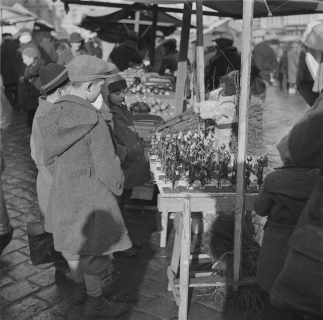 Damals 1935: Nikolaus und Krampus am Linzer Hauptplatz
Lange bevor sich schließlich die Christkindlmärkte durchsetzen konnten, fand alljährlich auf dem Linzer Hauptplatz ein dreitägiger Nikolomarkt statt. In den verschiedenen Buden wurden Lebzelten und Naschwaren aller Art angeboten, dazu Zwetschken- und Pelzkrampusse, Feigenweiberl, Dattelmanderl, Krampusruten und vieles mehr. Auch traditionell weihnachtliche Früchte wie Orangen durften nicht fehlen. | Foto: Archiv der Stadt Linz