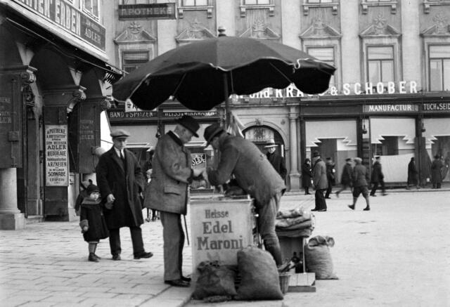 Damals 1930: Maronibrater auf dem Hauptplatz
Damals wie heute zählte der Maronibrater zu den Fixpunkten im vorweihnachtlichen Stadtbild. Die Maroni wurde in Südeuropa seit Jahrhunderten vor allem im Winter als Nahrungsquelle geschätzt. In unseren Breiten lassen sich bereits im 18. Jahrhundert Maronibrater nachweisen. Das Foto aus dem Jahr 1930 zeigt den Linzer Hauptplatz, im Hintergrund ist das Kaufhaus „Kraus &amp; Schober“ zu erkennen. | Foto: Archiv der Stadt Linz