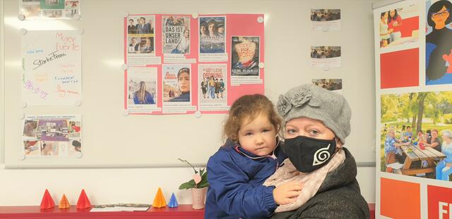 Yvonne aus Favoriten mit ihrer Tochter vor Filmplakaten über das Frauenwahlrecht.  | Foto: Salme Taha Ali Mohamed