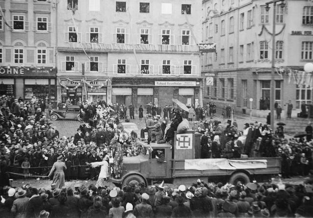 Damals 1939: Faschingsumzug auf dem Hauptplatz
Vor 80 Jahren wurde der erste große Faschingsumzug in Linz abgehalten. Angelehnt an die rheinische Karnevalstradition inszenierten die nationalsozialistischen Machthaber am 19. Februar 1939 unter dem Motto „Linz lacht und tanzt wieder“ einen Aufmarsch vom Hauptplatz bis zum Volksgarten. Im Bild macht man sich mit dem Kruckenkreuz und Verkleidungen über den untergegangenen Ständestaat und dessen Vertreter lustig. | Foto: Archiv der Stadt Linz