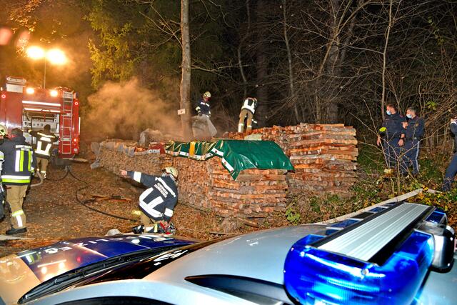 Ein Holzstapel hat aus unerklärlichen Gründen zu brennen begonnen. Die Polizei ermittelt in alle Richtungen.