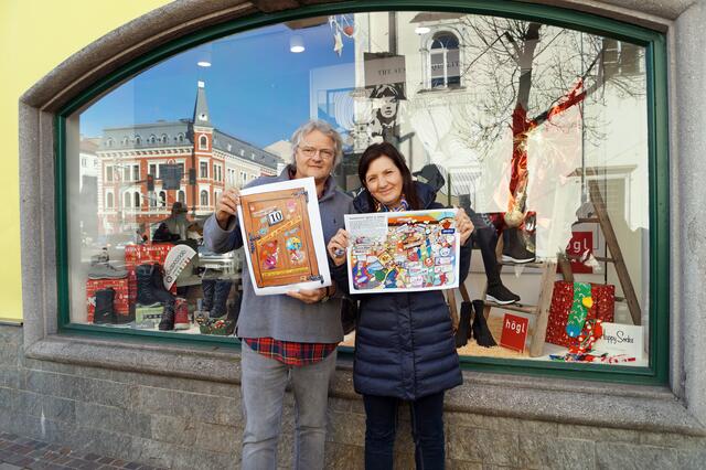 Anna und Jochen Meyer bringen Tag 10 des Comic Adventkalenders am Schaufenster an.