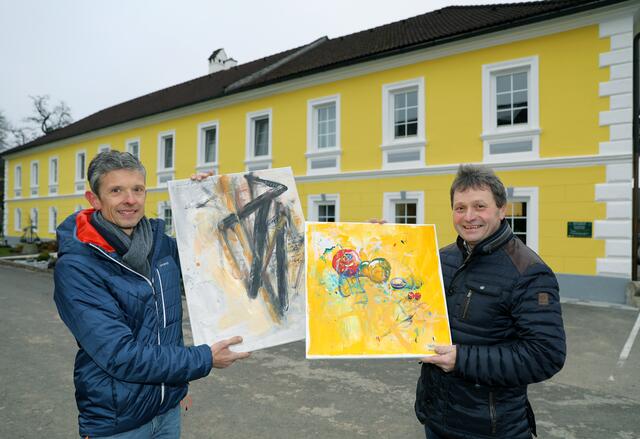 Der amtierende Präsident des Lions Club Amstetten Alexander Zechberger und „Seppelbauer“ Bernhard Datzberger mit zwei Kunstwerken der Lions-Kunstauktion vor dem Vierkanthof, der ab 1. Dezember als überdimensionaler Adventkalender fungiert.