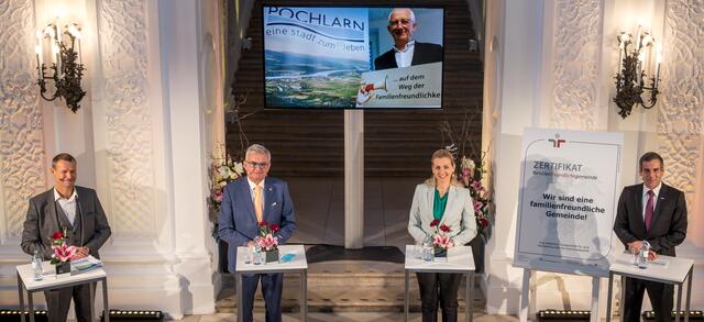 Christoph Jünger (Geschäftsführer Unicef), Alfred Riedl (Präsident des Österreichischen Gemeindebundes), Christine Aschbacher (Bundesministerin für Arbeit, Familie und Jugend) und Werner Sejka (Familie &amp; Beruf Management GmbH). Auf dem Großbildschirm zu sehen ist Pöchlarns Bürgermeister Franz Heisler. | Foto: Familie &amp; Beruf Management GmbH