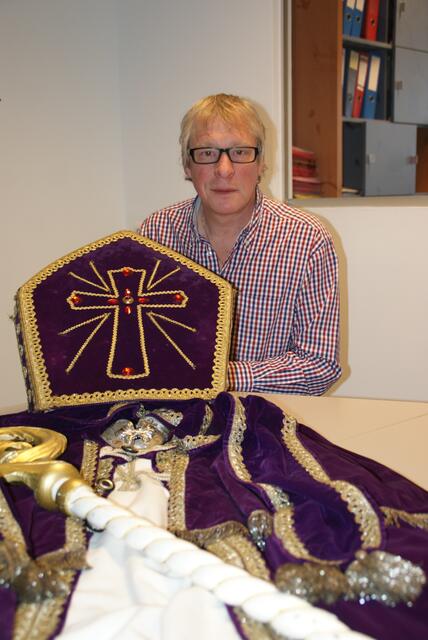 Richard Holfeld zeigt das traditionelle Bischofsgewand des Nikolaus mit Krummstab und Mitra (liturgische Kopfbedeckung).