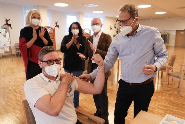 Bei der Covid-19 Impfung im Seniorenwohnhaus Salzburg-LIefering: Im Bild der ärztliche Leiter der städtischen Senioreneinrichtungen Randolf Messer bei der Impfung von Seniorenwohnhaus-Arzt Leonhard Hofer. Im Hintergrund von links: Stadträtin Anja Hagenauer, Seniorenwohnhausleiterin Andrea Sigl und Landeshauptmannstellvertreter Christian Stöckl.